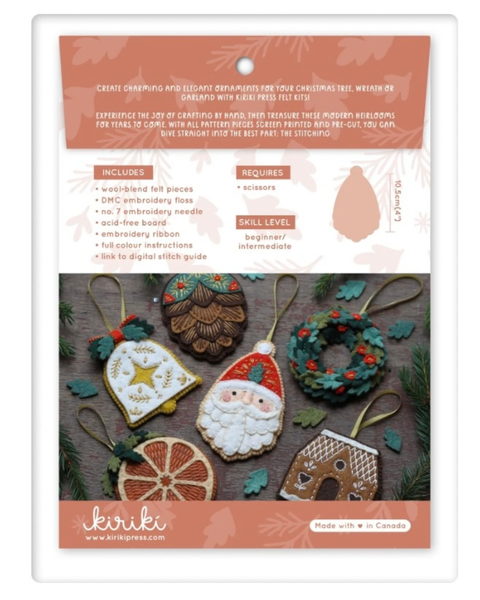 A packaged Christmas ornament crafting kit by Kiriki, featuring a white card with coral and brown panels, product details, and several sample holiday ornaments including a Santa Claus ornament, a gingerbread man ornament, a wreath, and a pinecone ornament.