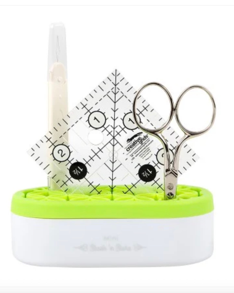 Set of scissors and ruler in a green and white container on a white background