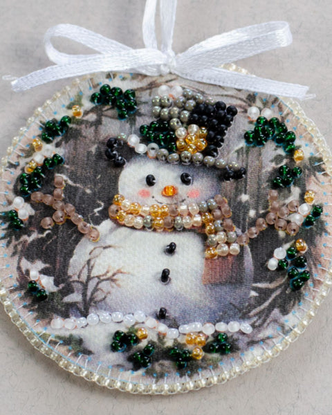 Decorative ornament with a snowman and beaded embellishments on a neutral background