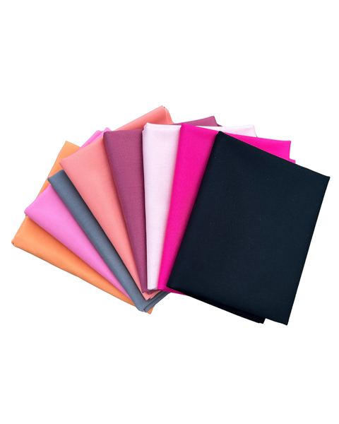 A fan arrangement of folded fabric in multiple colours, including orange, pink, purple, white, and black in front, shown on a plain white background.