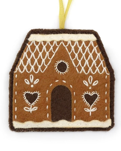A gingerbread house shaped felt ornament with white embroidered details, a dark brown arched doorway, a yellow hanging ribbon, and a white background.