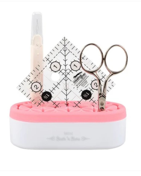 Pink and white sewing station with scissors, ruler, and pen on a white background