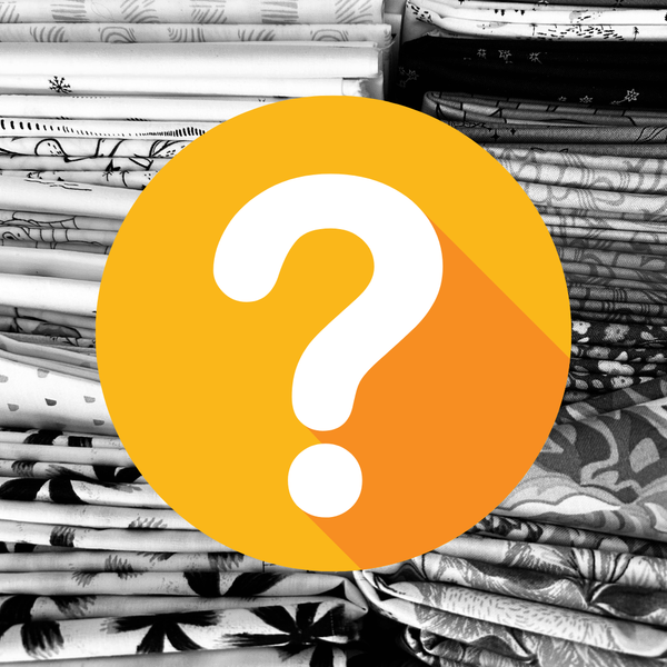 A large orange and yellow circular graphic with a white question mark overlaid on a background of stacked folded fabrics in black and white patterns.