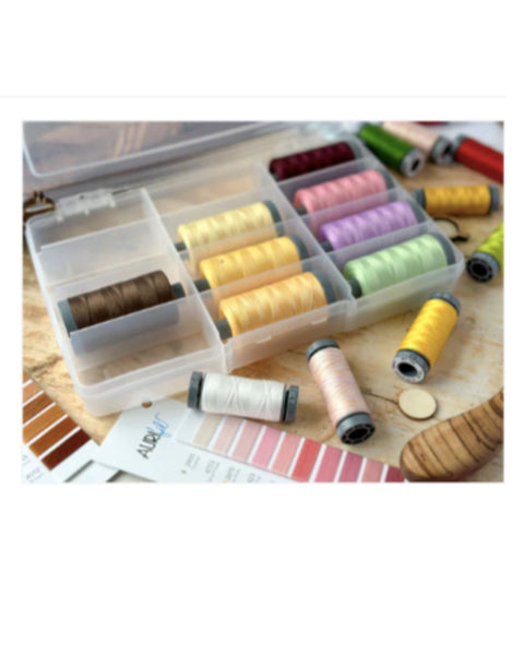 Set of colorful thread spools in a clear plastic case on a wooden surface.