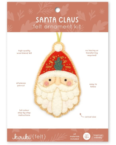 Santa Claus felt ornament kit by Kiriki (felt) on a white card with a peach header. The package shows a completed felt ornament of Santa with a red hat, green tree, and white beard, plus text describing the kit contents and instructions.