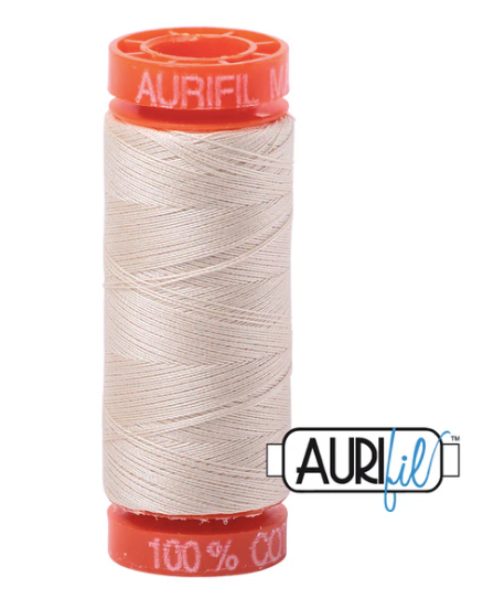 Spool of Aurifil thread with red cap on a white background