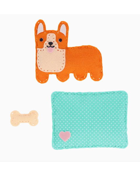 A felt dog toy and matching pet toy mat on a white background. The felt dog is orange with a cream-colored snout and inner ears, and the matching rectangular mat is mint green with white polka dots and a small pink heart.