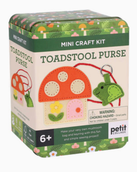 A Petit Collage Toadstool Purse mini craft kit in a decorative tin box, featuring illustrations of a mushroom house and a green frog purse on a white and green background.