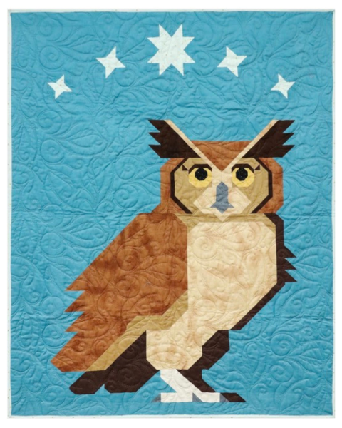 A quilted wall hanging or blanket featuring a stylized owl in brown, beige, and black tones on a bright blue background with white stars.